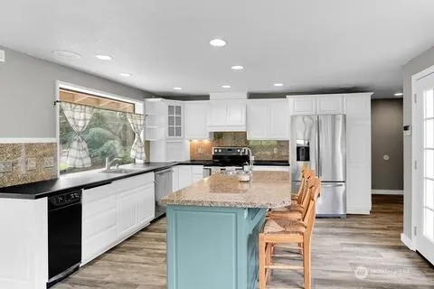 a kitchen with stainless steel appliances granite countertop a stove top oven a sink refrigerator and cabinets