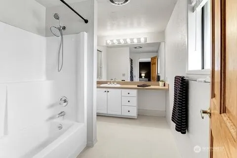 a bathroom with a double vanity sink mirror and bathtub