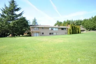 a view of a house with a big yard and large trees