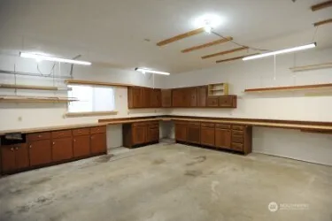 a large kitchen with a large counter top a sink stainless steel appliances and cabinets