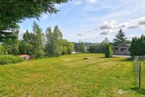 a yard with swimming pool and trees in the background