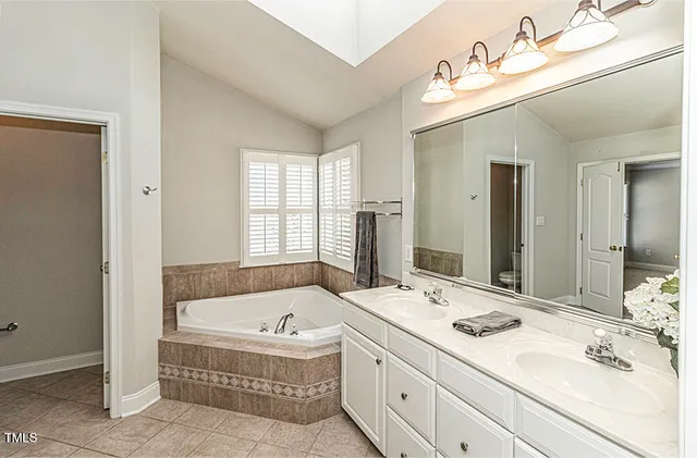 a bathroom with a tub double sink window and mirror