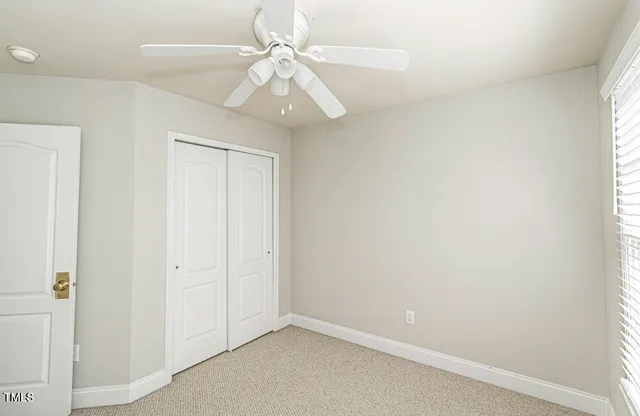 an empty room with a chandelier fan and a window