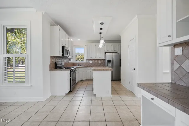 a kitchen with granite countertop white cabinets white appliances a sink and a window