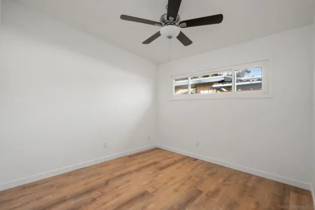 a view of an empty room with window and wooden floor