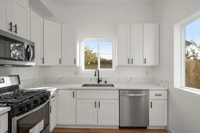 a kitchen with cabinets stainless steel appliances a sink and wooden floor