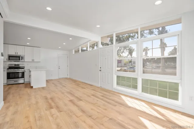 a kitchen with stainless steel appliances a refrigerator stove a sink and white cabinets with wooden floor