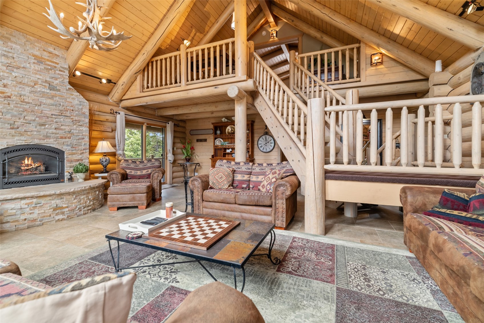 243 Rena Road Breckenridge, CO 80424 - Photo 34 of 50 Tiled living room featuring a chandelier, wooden ceiling, a stone fireplace, high vaulted ceiling, and rustic walls