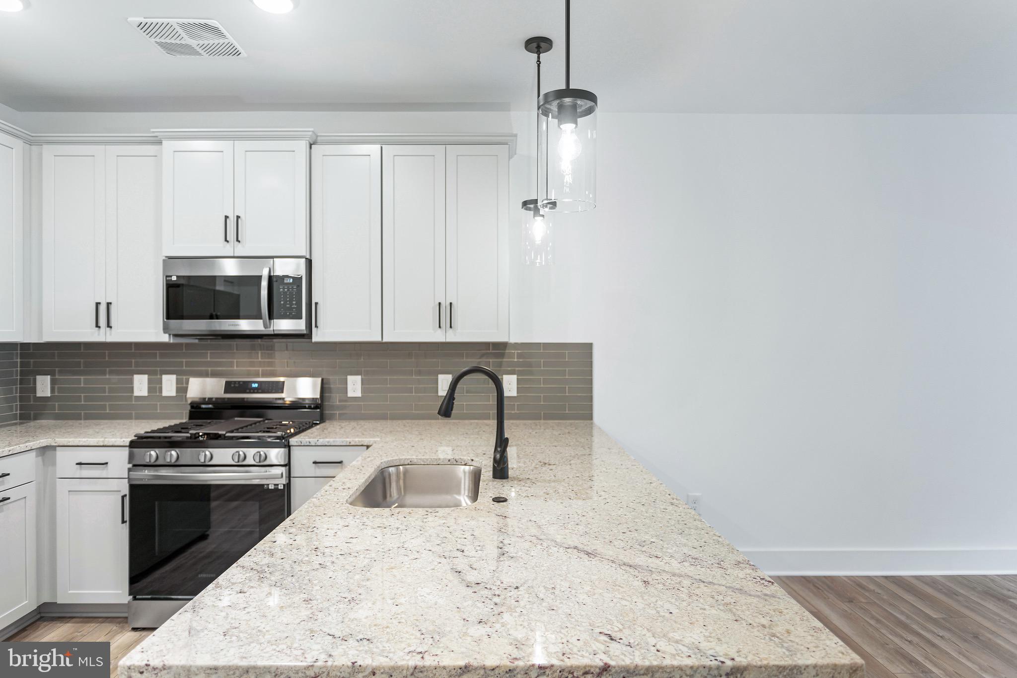 78 Old Mill Bottom Road North, Unit 107 Annapolis, MD 21409 - Photo 20 of 39 a kitchen with granite countertop a stove a sink and a microwave