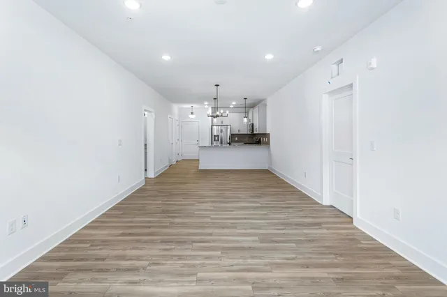 a view of a kitchen with kitchen island a sink wooden floor and a refrigerator