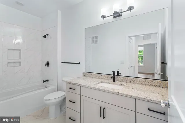 a bathroom with a granite countertop toilet a sink and a mirror