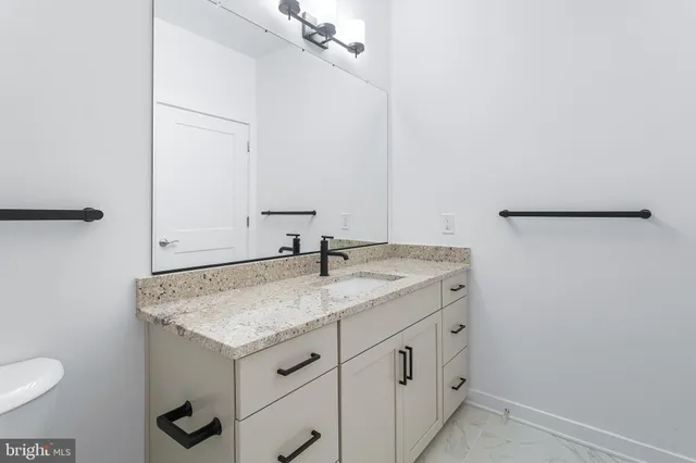 a bathroom with a granite countertop sink and a mirror