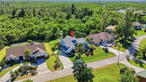an aerial view of residential house with outdoor space and trees all around