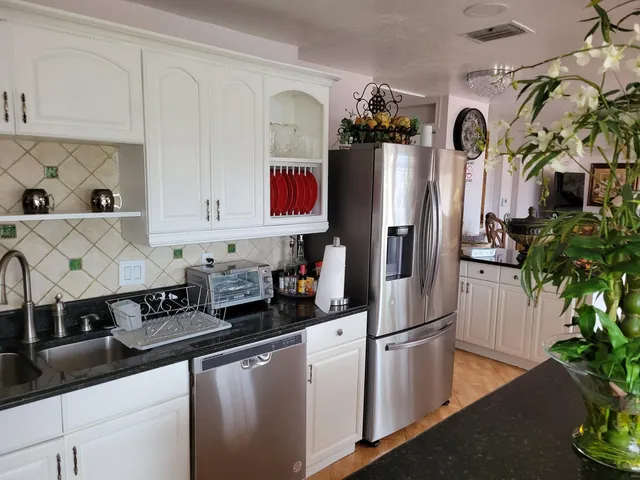 a kitchen with stainless steel appliances granite countertop a refrigerator a stove and a white wooden cabinets