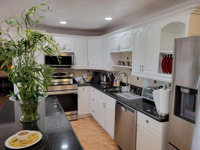a kitchen with stainless steel appliances a sink a stove a refrigerator cabinets and a window