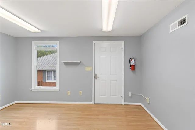 an empty room with wooden floor and windows