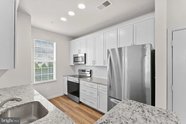 a kitchen with stainless steel appliances granite countertop a refrigerator sink and stove