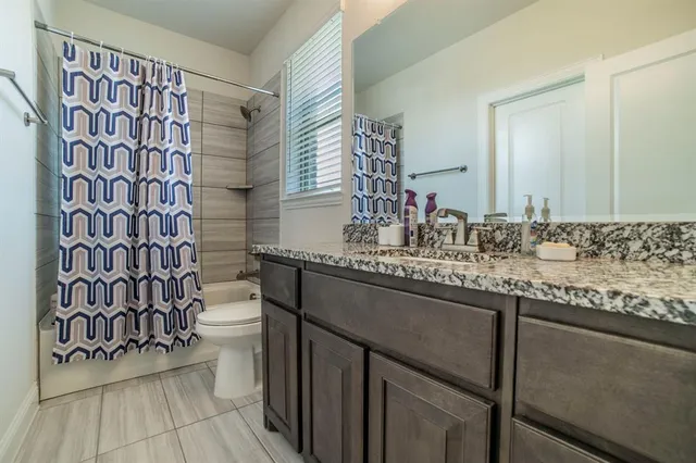 a bathroom with a granite countertop sink a mirror and shower