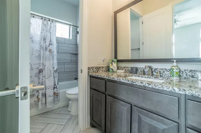 a bathroom with a granite countertop sink toilet and shower