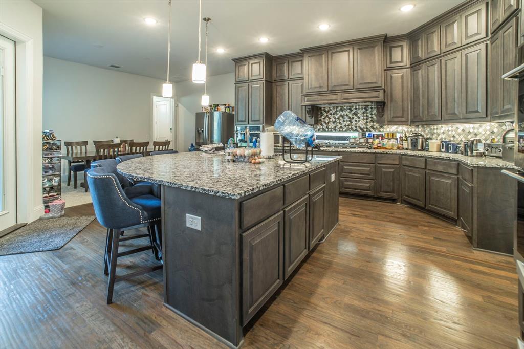 1420 Ashton Ridge Drive Prosper, TX 75078 - Photo 7 of 39 a kitchen with stainless steel appliances granite countertop a table chairs sink and cabinets
