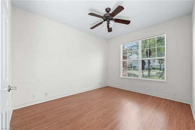 an empty room with a window and a fan