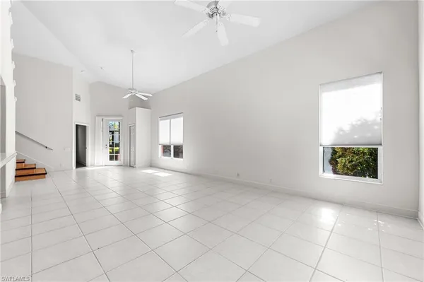 an empty room with a chandelier fan and windows