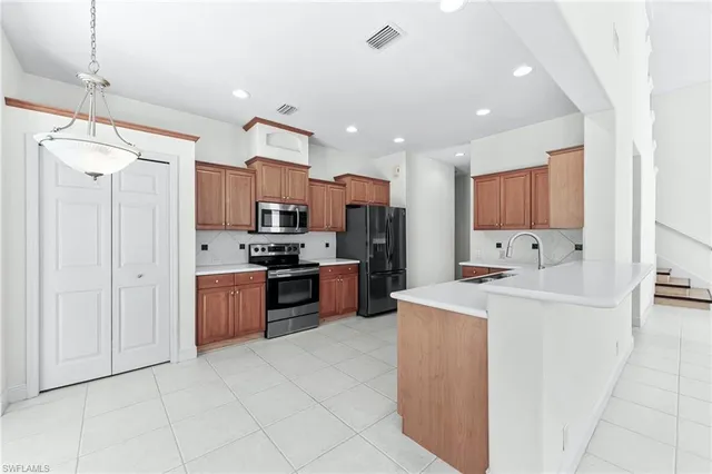 a kitchen with stainless steel appliances kitchen island granite countertop a refrigerator and a stove top oven