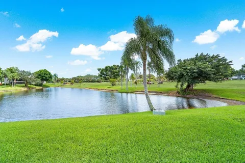a view of a lake with a big yard and palm trees