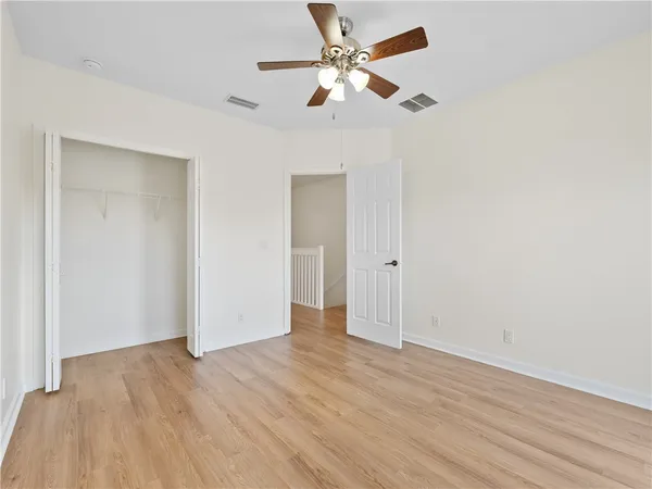 an empty room with wooden floor ceiling fan and window