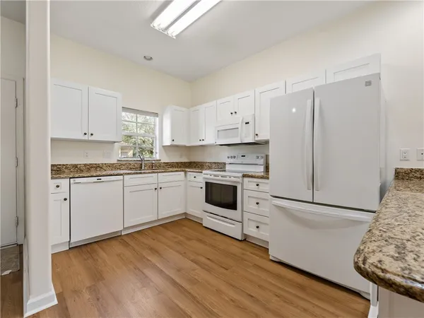 a kitchen with granite countertop white cabinets and white appliances