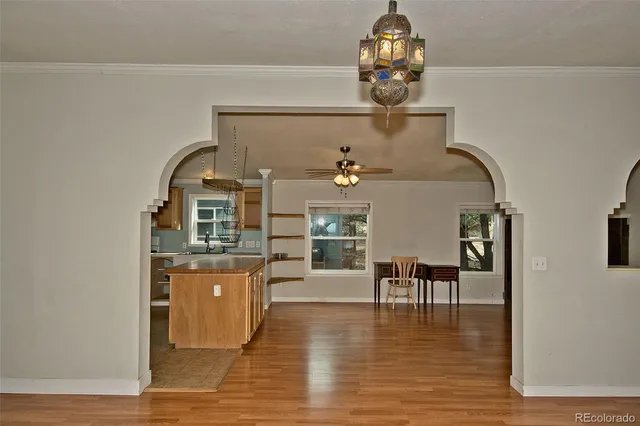 a dining room with wooden floor a chandelier a wooden table and chairs