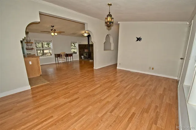 an empty room with wooden floor and a hallway