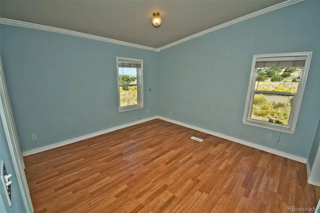 a view of empty room with window and wooden floor