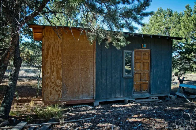 a wooden door covered with trees in the background