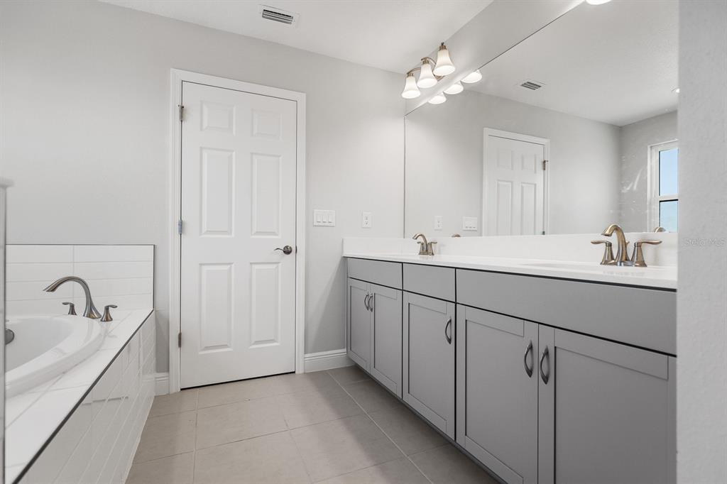 14671 Horse Trot Road Lithia, FL 33547 - Photo 19 of 40 a bathroom with a double vanity sink a mirror and a bathtub
