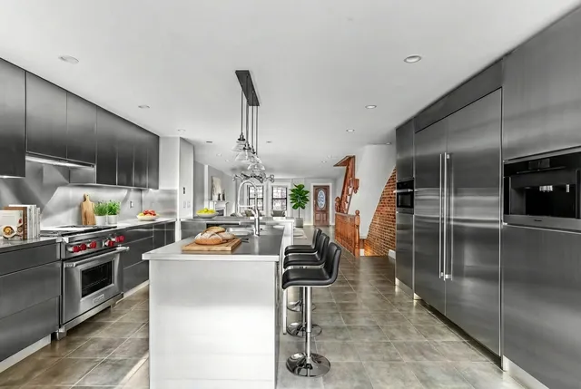 a kitchen with stainless steel appliances kitchen island granite countertop a table chairs sink and cabinets