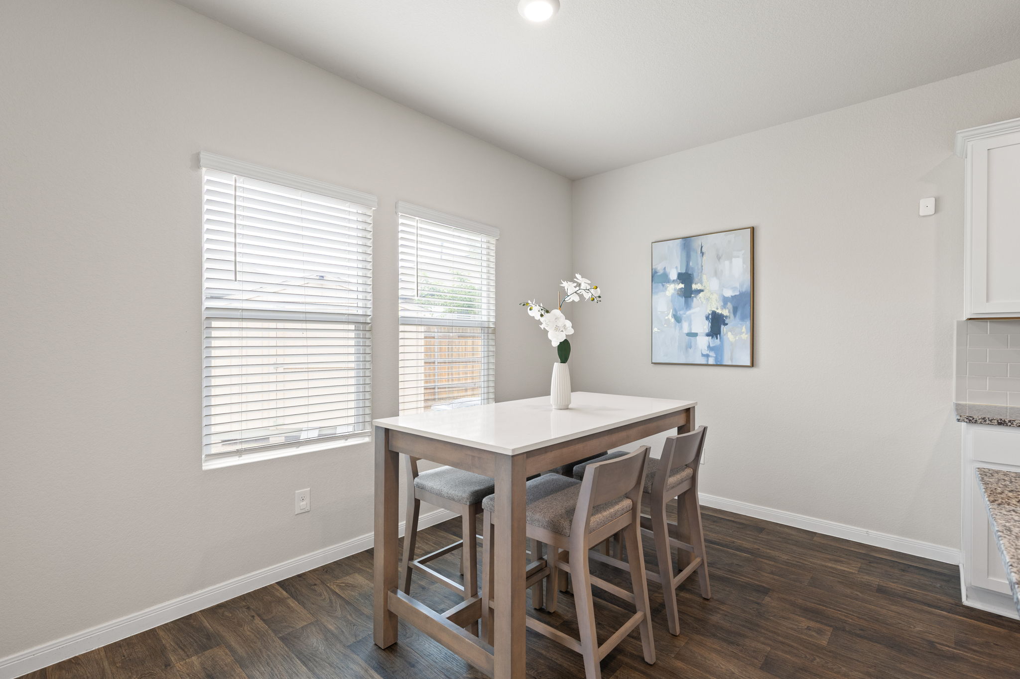 281 Jayden Drive Kyle, TX 78640 - Photo 17 of 36 Light-filled dining area featuring wood-finish flooring, two large windows with blinds, a recessed ceiling light, and a white baseboard trim