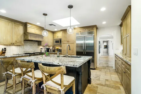 a kitchen with stainless steel appliances granite countertop a sink a stove and refrigerator