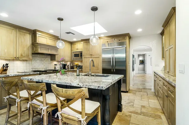 a kitchen with stainless steel appliances granite countertop a sink a stove and refrigerator