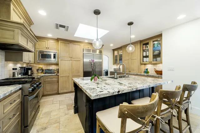 a kitchen with granite countertop kitchen island stainless steel appliances a sink stove and refrigerator
