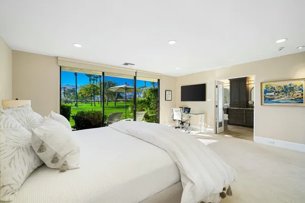 a large bedroom with a bed and flat tv screen on the dresser