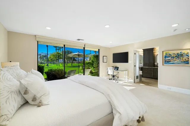 a large bedroom with a bed and flat tv screen on the dresser