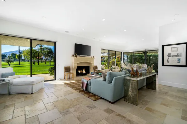 a living room with furniture a fireplace and a floor to ceiling window
