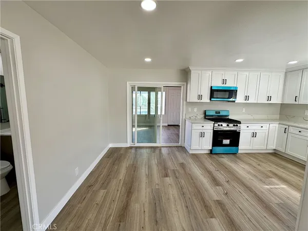 a large kitchen with granite countertop a stove top oven a sink dishwasher and a fireplace with wooden floor