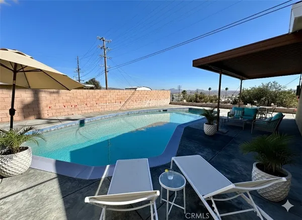 a backyard of a house with table and chairs under an umbrella