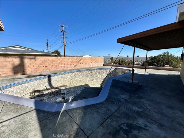 a view of patio with table and chairs under an umbrella with a small yard