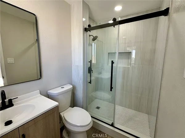 a bathroom with a shower a sink mirror and toilet