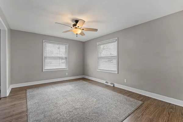 an empty room with windows and ceiling fan
