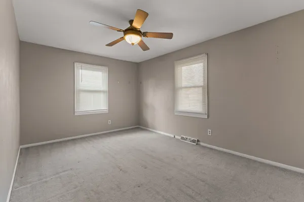 an empty room with windows and ceiling fan