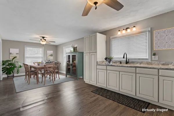 a kitchen with granite countertop a refrigerator a stove a dining table and chairs with wooden floor